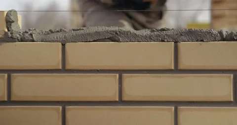 Professional bricklayer puts last two bricks in row, trowel levels bricks Stock Footage 130368001