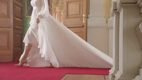 Professional bride gracefully lifting pristine wedding gown while walking Stock Footage 306396734