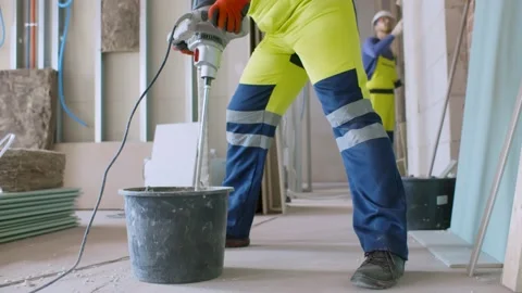 Professional builder blending mixture in bucket using construction mixer Stock Footage 133638377