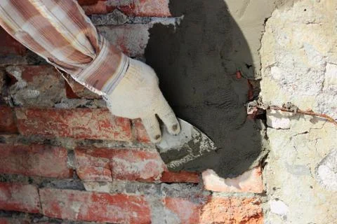 A professional builder bricklayer with hand trowel applies cement mortar Stock Photos