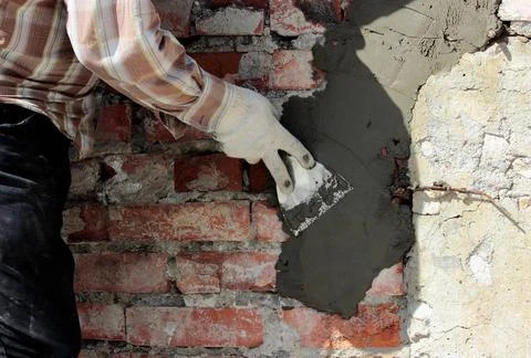 A professional builder bricklayer with hand trowel applies cement mortar t... Stock Photos