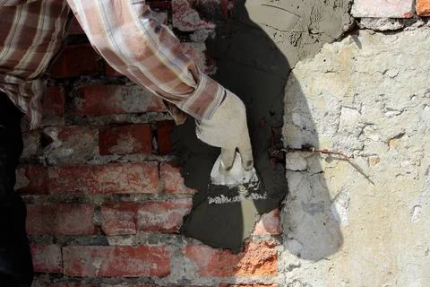 A professional builder bricklayer with hand trowel applies cement mortar t... Stock Photos