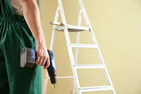 Professional builder with drill indoors, space for text. Home repair service Stock Photos
