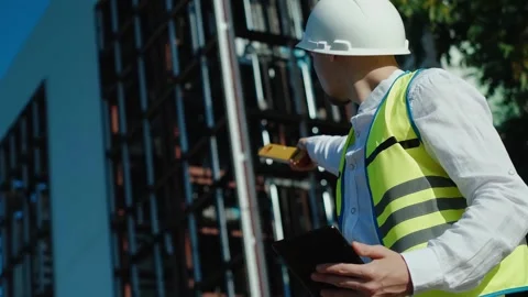 A professional builder in a KN 95 mask and hard hat at a construction site is ta Stock Footage 249262982
