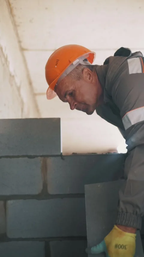 A professional builder is laying concrete blocks to construct a wall Stock Footage 346703542
