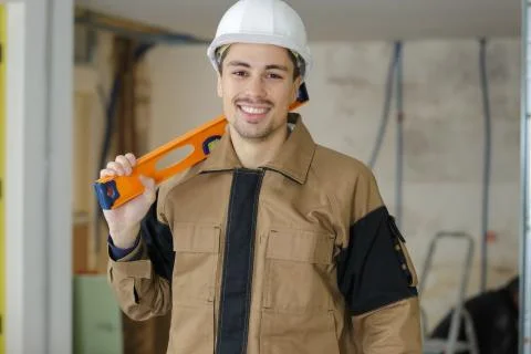 Professional builder posing with spirit level at construction site Stock Photos