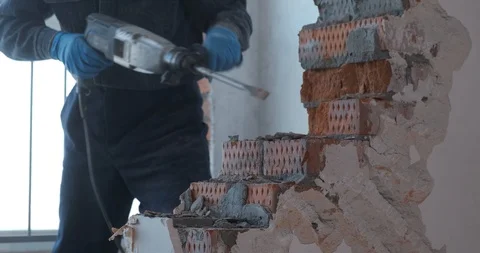 Professional builder with a puncher in the hands breaks a brick wall. Close-up Stock Footage 128232393