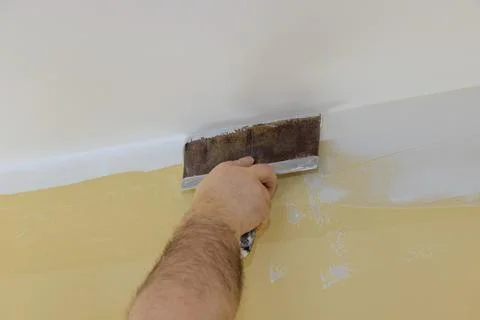 Professional builder smooths wall with spatula putty put on leveled surface o Stock Photos