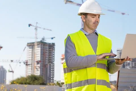 Professional builder standing with notebook in front of the construction site Foto stock