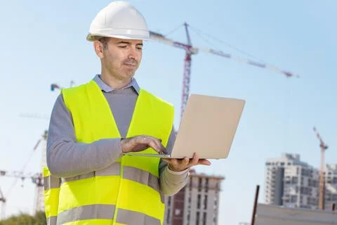 Professional builder standing with notebook in front of the construction site Stock Photos