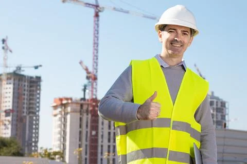 Professional builder standing with notebook in front of the construction site Foto stock
