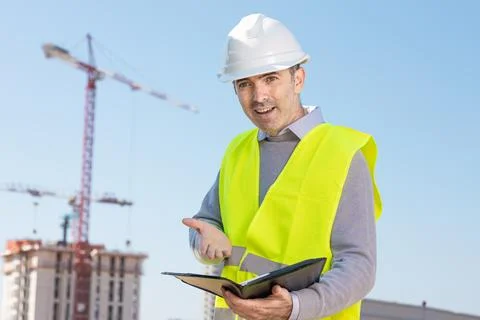 Professional builder standing with notebook in front of the construction site Foto stock