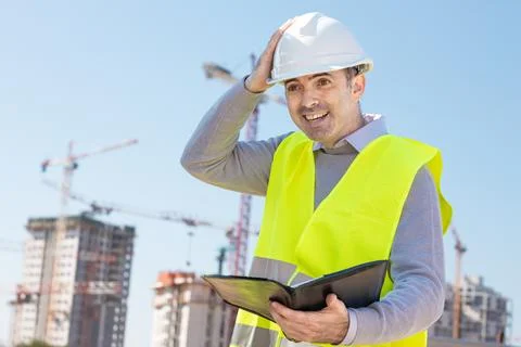 Professional builder standing with notebook in front of the construction site Stock Photos