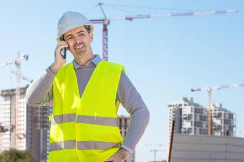 Professional builder standing talking on a phone in front of the constructi.. Foto stock
