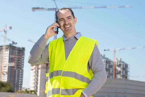 Professional builder standing talking on a phone in front of the constructi.. Foto stock