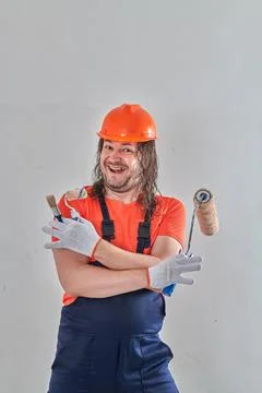 A professional builder stands in gloves with a roller and a brush Stock Photos
