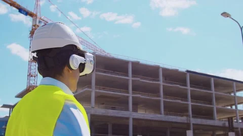 Professional builder in VR helmet standing in front of construction site and Stock Footage 137772394
