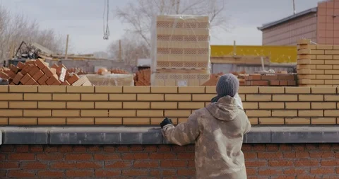 Professional builder wipes brick wall after his work. Worker builds house. Build Stock Footage 128938672
