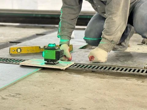 Professional builder worker installing floor a large ceramic tile using a l.. Stock Photos
