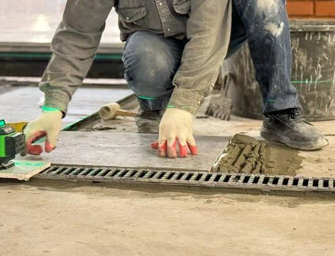 Professional builder worker installing floor a large ceramic tile using a l.. Stock Photos