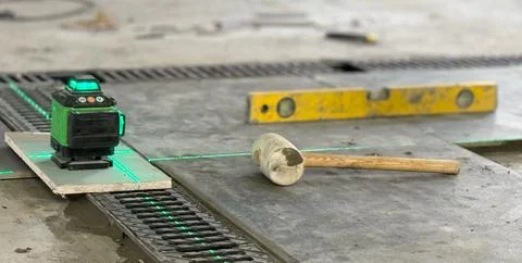 Professional builder worker installing floor a large ceramic tile using a l.. Stock Photos