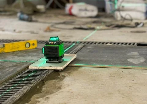 Professional builder worker installing floor a large ceramic tile using a l.. Stock Photos