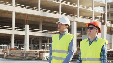 Professional builders standing in front of construction site. Office building Stock Footage 138514123