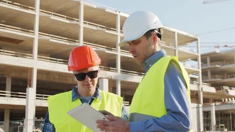 Professional builders standing in front of construction site. Office building Stock Footage 138514256