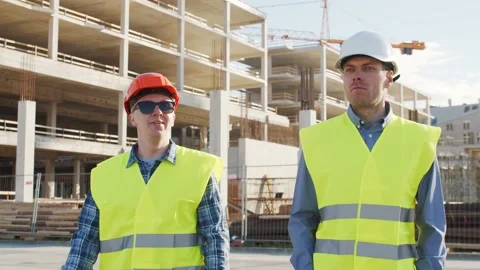 Professional builders standing in front of construction site. Office building Stock Footage 138601318