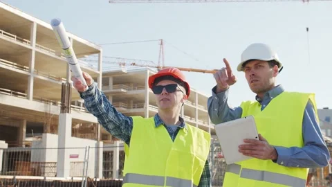 Professional builders standing in front of construction site. Office building Stock Footage 138677967