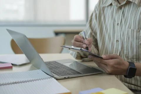 Professional businessman using laptop computer and making notes on notepad. 스톡 사진