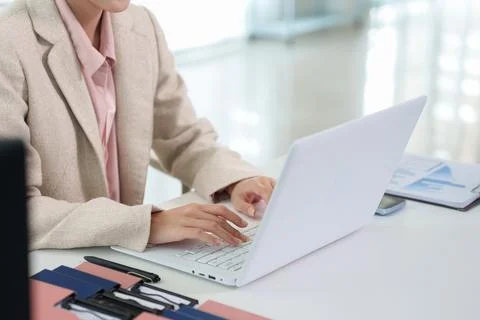 Professional businesswoman using laptop computer typing working in bright m.. Fotos Stock