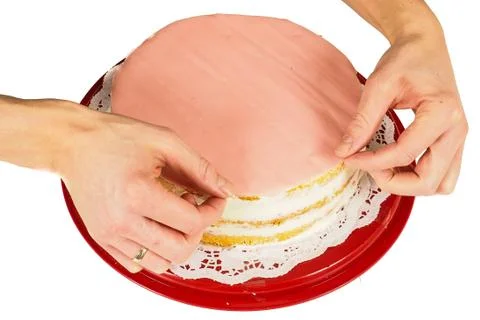 Professional cake baker making the final touch when covering a cream cake wit Stock Photos