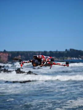 Professional camera drone hovering over rocky coast and ocean waves Stock Photos