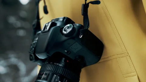 Professional camera hanging on the background of a yellow jacket Stock Footage 144696034