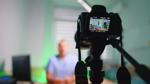 Professional camera on tripod with a man on the display. Medic creates video for Stock Footage 334339262
