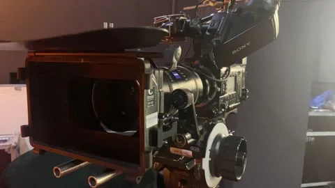 Professional camera with zoom lens, many buttons and toggle switches stands on Stock Footage 237468565