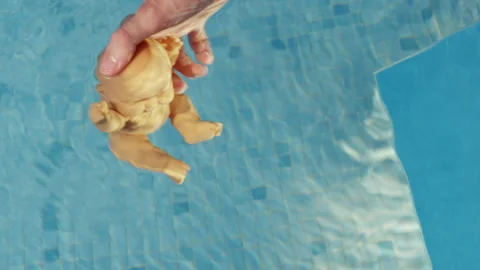 Professional cameraman dips doll into water in swimming pool Stock Footage 229722091