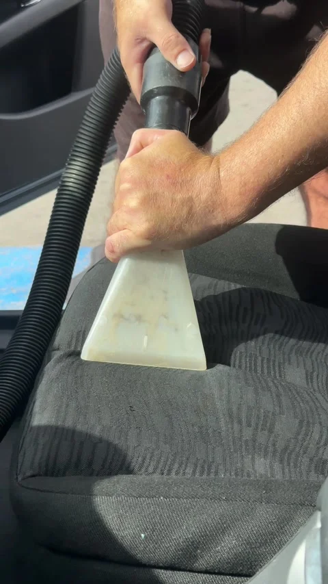 Professional car detailer using an extractor vacuum for deep cleaning a dirty Stock Footage 345424727
