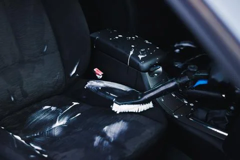 Professional car detailing process with cleaning foam applied on dark fabri.. Stock Photos