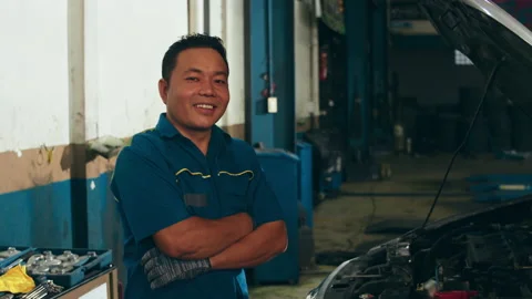 Professional car mechanic looking at camera and smiling at repair service. Stock Footage 153793635