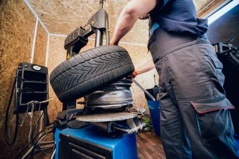 Professional car mechanic replace tire on wheel. 스톡 사진