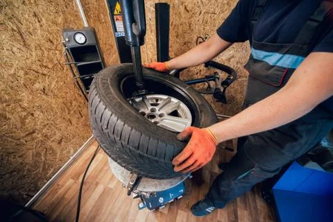 Professional car mechanic replace tire on wheel. Stock Photos