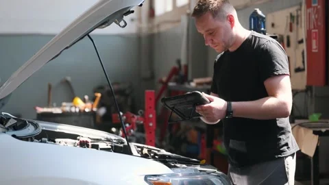 Professional car mechanic working in auto repair service with tablet Stock Footage 299725437