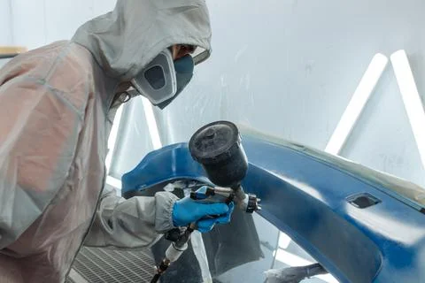 Professional car painter is painting in garage by airbrush. Stock Photos