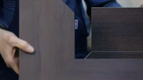 Professional carpenter manually assembles expensive composite door, workshop Stock Footage 128389973