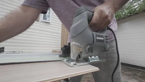 Professional carpenter using electric jigsaw for precision wood cutting outside Stock Footage 340566038