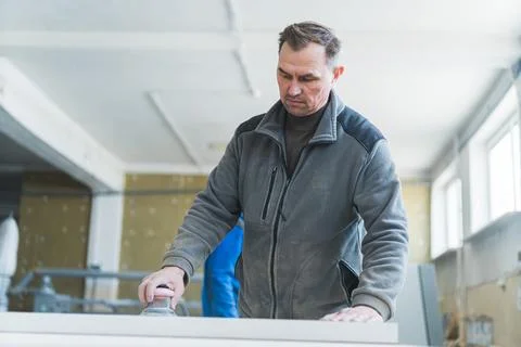 Professional carpenter using a sander while working on wood at the workshop Stock Photos