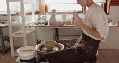 Professional ceramist at work using tools for creating handmade cup in studio Stock Footage 208075459