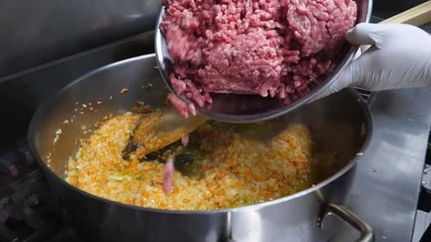 Professional Chef Adding Fresh Ground Meat to Sautéed Soffritto Vegetables for A Stock Footage 337678324